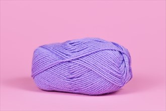 Single violet ball of wool on pink background