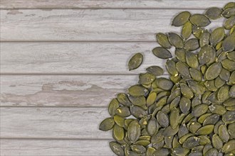 Pumpkin seeds on side of wooden background with copy space