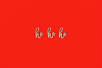 Seasonal Christmas wooden letters forming words 'ho ho ho' on red background