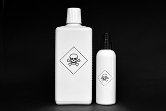 Two white bottles with poison warning signs on them on black background