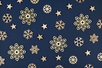 Christmas flat lay with golden snowflake and star ornaments on dark blue background