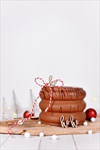 Layered spit cake called 'Baumkuchen' glazed with chocolate in front of seasonal Christmas decoration
