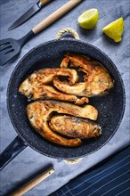 Slices of baked carp fish in a pan