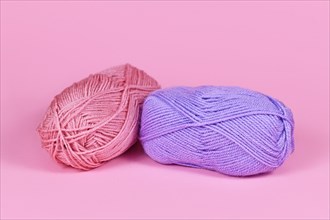 Two balls of wool on pink background