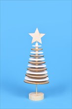 Wooden Christmas tree decoration made of wooden round plates on blue background