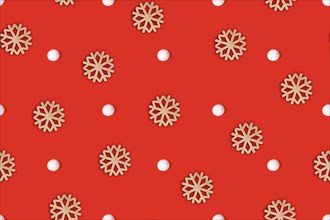 Simple seamless top view flat lay with wooden snowflake ornaments and white snowballs arranged on bright red background