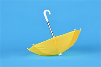 Yellow doll umbrella upside down on blue background