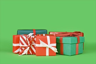 Various small Christmas gift boxes on green background with copy space