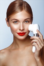 Beautiful girl with red lips and classic makeup with massage brush in hand. Beauty face. Photo taken in the studio