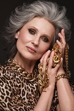 Portrait of a beautiful elderly woman in a leopard blouse with classic makeup and gray hair