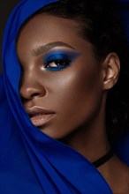 Beautiful black woman with blue fabric and classic art make-up. Beauty face. Photo taken in the studio