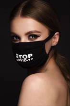 Portrait of a beautiful woman in a black mask stop covid and classic makeup. Mask mode during the covid pandemic