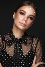 Portrait of a beautiful woman in a black dress with pearls and classic makeup. Beauty face