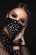 Portrait of a beautiful woman in a black mask with pearls and classic makeup. Mask mode during the covid pandemic