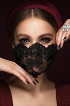 Portrait of a beautiful woman in a black lace mask and classic makeup. Mask mode during the covid pandemic