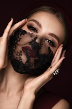 Portrait of a beautiful woman in a black lace mask and classic makeup. Mask mode during the covid pandemic