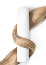 A strand of blond hair with a bottle of shampoo on a white background. Close-up