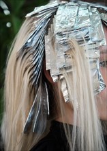 A young woman in a hairdressing salon dyes her hair blond. Hair coloring process