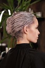 Young woman in a hairdressing salon dyes her hair blond and washing head