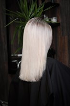Young woman in a hairdressing salon after coloring her hair blond. beauty face and hair. Back view