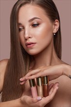 Beautiful young girl with natural nude make-up with cosmetic in hands. Beauty face. Photo taken in studio