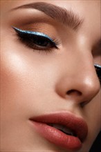 Beautiful girl with sexy lips and classic makeup with cosmetic blue eyeliner. Beauty face. Photo taken in the studio