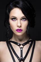 Beautiful Girl in the Gothic style with leather accessories and bright makeup. Beauty face. Picture taken in the studio on a black background