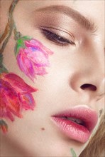 Beautiful blond girl with tresses and a floral pattern on the face. Beauty flowers. Portrait shot in studio