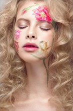 Beautiful blond girl with tresses and a floral pattern on the face. Beauty flowers. Portrait shot in studio