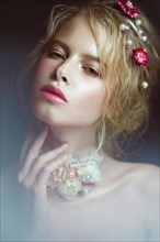 Beautiful blond fashion girl with flowers on the neck and in her hair