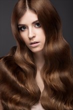 Beautiful brunette girl with a perfectly curls hair and classic make-up. Beauty face. Picture taken in the studio