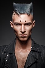 Young man with blue hair and creative makeup and hair. Photo taken in the studio