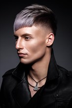 Young man with purple hair and creative makeup and hair. Photo taken in the studio