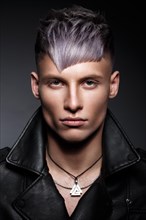 Young man with purple hair and creative makeup and hair. Photo taken in the studio