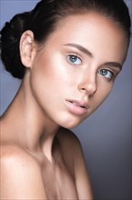 Beautiful young girl with a light natural make-up. Beauty face. Picture taken in the studio on a grey background