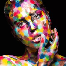 Girl with colored face painted. Art beauty image. Picture taken in the studio on a black background