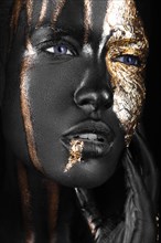 Fashion portrait of a dark-skinned girl with gold make-up.Beauty face. Picture taken in the studio on a black background