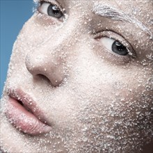 Portrait of a girl with pale skin and sugar snow on her face. Creative art beauty fashion. Picture taken in the studio on a blue background