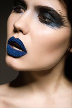 Portrait of beautiful girl with unusual blue lips and eyes closed. Picture taken in the studio on a gray background