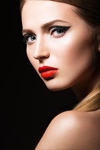 Beautiful young girl with a bright make-up and red nails. Picture taken in the studio on a black background