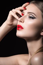 Beautiful young girl with a bright make-up and red nails. Picture taken in the studio on a black background