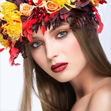 Beautiful girl with bright autumn wreath of leaves and flowers. Beauty face. Picture taken in the studio on a white background