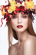 Beautiful girl with bright autumn wreath of leaves and flowers. Beauty face. Picture taken in the studio on a white background