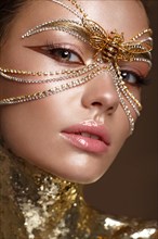 Beautiful girl in a golden mask and bright evening make-up. Beauty face. Photo taken in studio