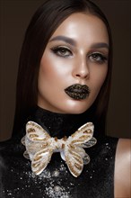 Beautiful girl with black creative art make-up and gold accessories. Beauty face. Photos shot in studio