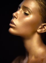 Beautyful girl with gold glitter on her face.Art image beauty face. Picture taken in the studio on a black background