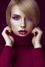 Beautiful blonde woman in a red sweater with bright makeup and dark lips. Beauty face. Picture taken in the studio
