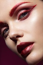 Beautiful girl with a bright red fashion makeup and crystals on the face. Close-up portrait. Beauty face. Picture taken in the studio