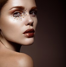 Beautiful girl with a gentle make-up and crystals on the face. Beauty face. Picture taken in the studio