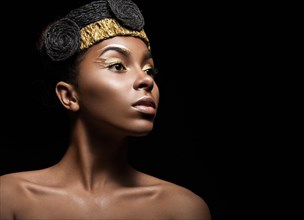 African girl with bright makeup and creative gold accessories on the head. Beauty face. Picture taken in the studio on a black background